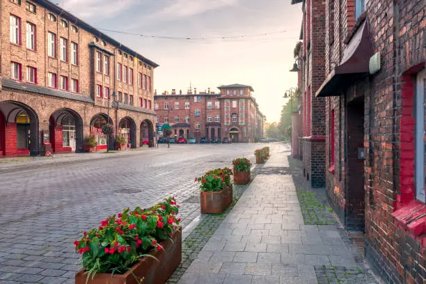 Traditional, silesian district Nikiszowiec. Renovated, old, brick block houses, build for coal miners in 1908-1919, cobblestone street. Beautiful, morning light. Katowice, Silesia, Poland.