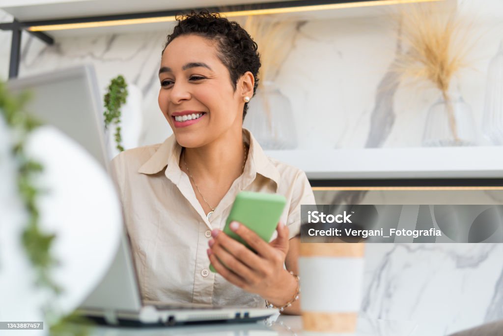 woman working with mobile and laptop black woman working with mobile and laptop at home Women Stock Photo
