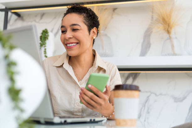 женщина, работающая с мобильным телефоном и ноутбуком - happiness african ethnicity cheerful businesswoman стоковые фото и изображения