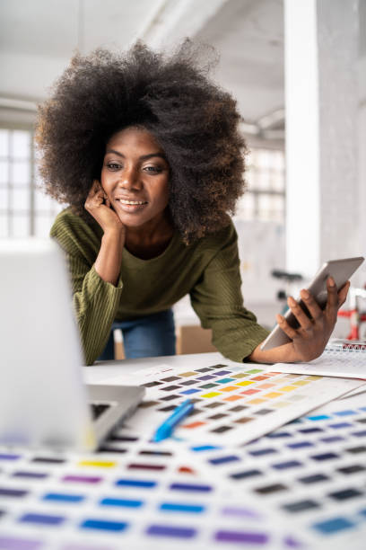 istock Smiling afro female designer in a creative office, working on laptop 1343889377