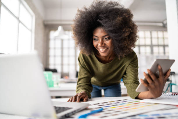 istock Smiling afro female designer in a creative office, working on laptop 1343889380