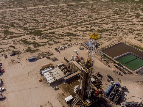 Fracking Drilling Rig Evening Shot under dramatic Sky in West Texas with Settling Ponds on the Prairie