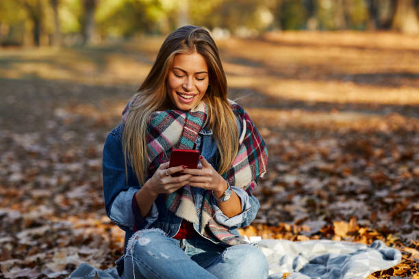 istock Young woman in the park using smartphone and smiling 1343890192