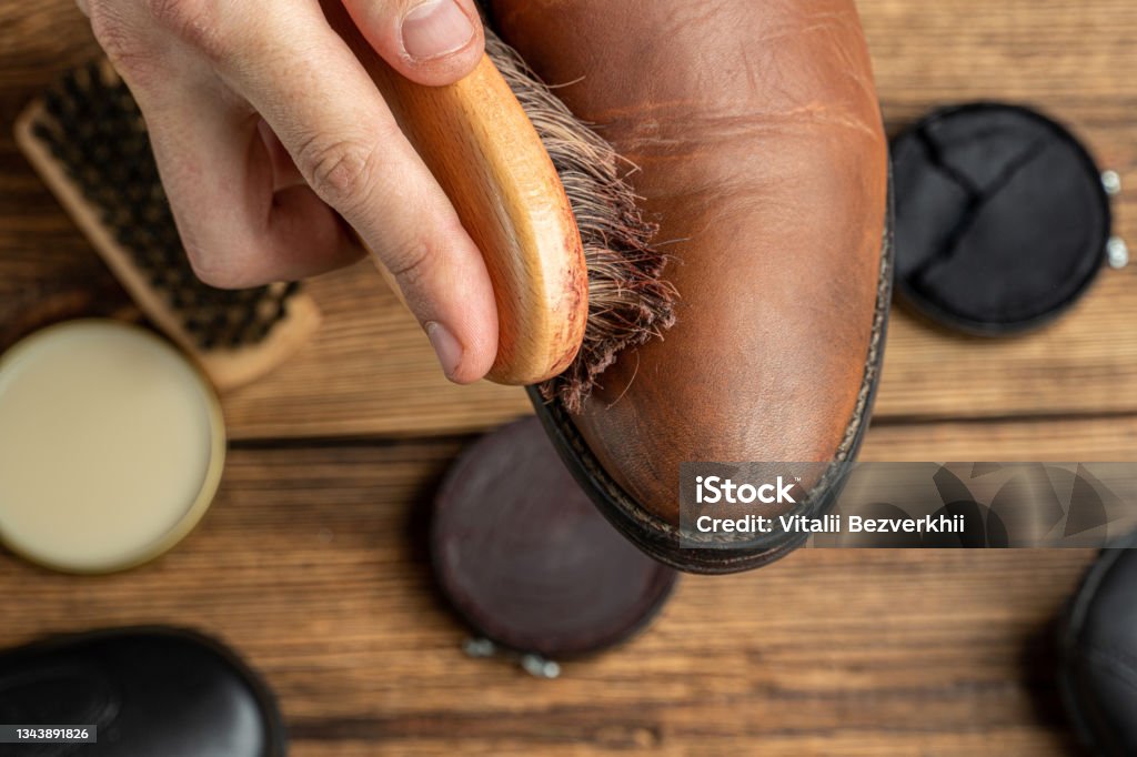 cleaning, polishing, restoration brown leather boots with brush and footwear care product, shoe polish Restoring Stock Photo