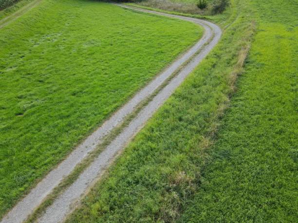 istock View from above of curved gravel road between grass fields 1343895094