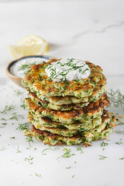 Greek Zucchini and Feta Fritters Greek Zucchini and Feta Fritters (Keftedes) with Green Onion, Dill and Tzatziki tzatziki stock pictures, royalty-free photos & images