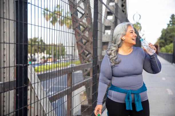 Senior Mexican Woman Drinking Water A senior Mexican woman drinking water after a workout fat nutrient stock pictures, royalty-free photos & images