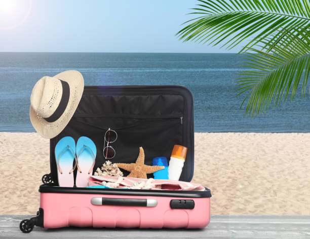 istock Suitcase with different beach objects on grey wooden table near sea 1343896955