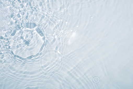 Light blue water background with circles from drops and stains all over the surface