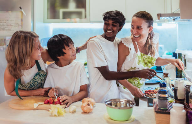 a multiracial family has fun cooking together at home. lesbian couple and multiracial family concept. adoption. - homosexual family lesbian parent imagens e fotografias de stock