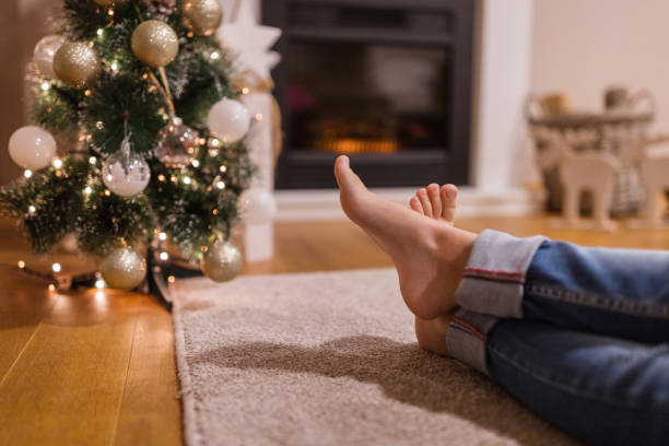 istock Barefoot person sitting on floor by a Christmas tree 1343900388