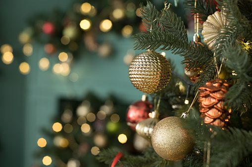 istock Bola de navidad de regalo en el árbol de Navidad rodeada de luces festivas. 1343907366