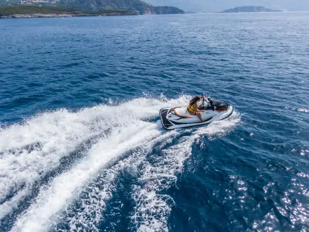 Photo of Aerial view of jet skier in blue sea. Jet ski in turquoise clear water racing stock photo