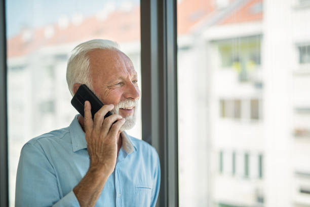 istock Senior man talking on phone and looking through window. 1343962922