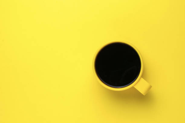 istock Yellow mug with black coffee on a yellow background. Flat lay. 1343970872