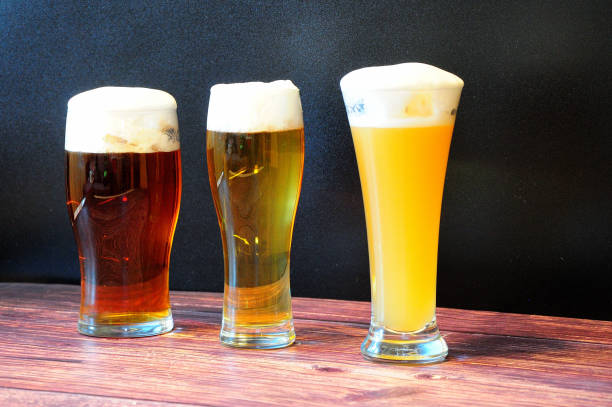 istock Three different glass goblets with wheat, light and dark beer are on a wooden table. 1343970921