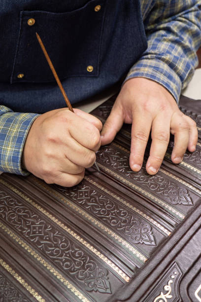 istock Bookbinder makes a unique cover for book. Handmake leather bookcover. 1343972435