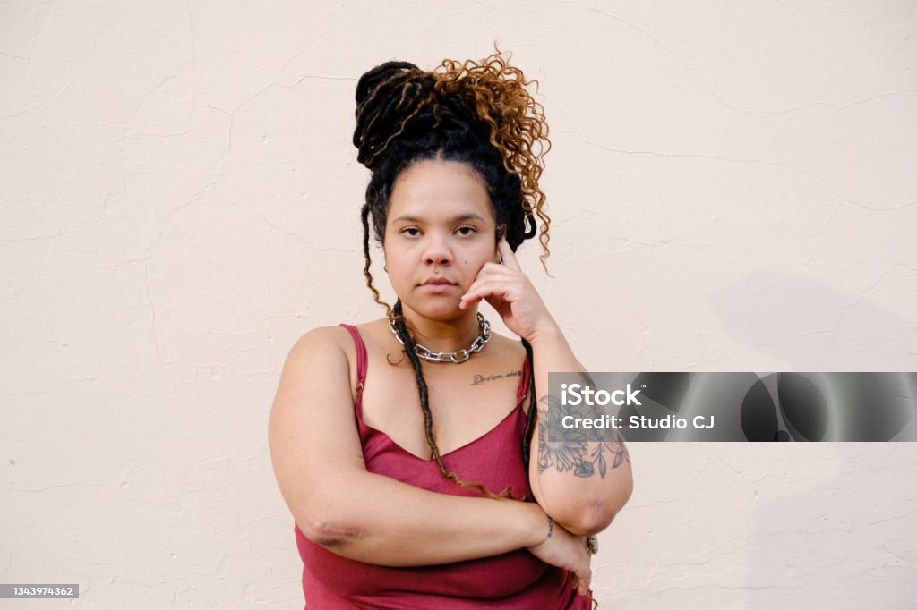 Young african-descent woman with dreadlocks looking at camera. Beauty with darker skin on a neutral background. Tattoo Stock Photo