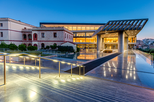 Athens, Greece - September, 09th 2019: Entrance of the illuminated modern architecture Acropolis Museum from the Dionisiou Areopagitou Promenade up to the Acropolis at Twilight. Athens, Greece.