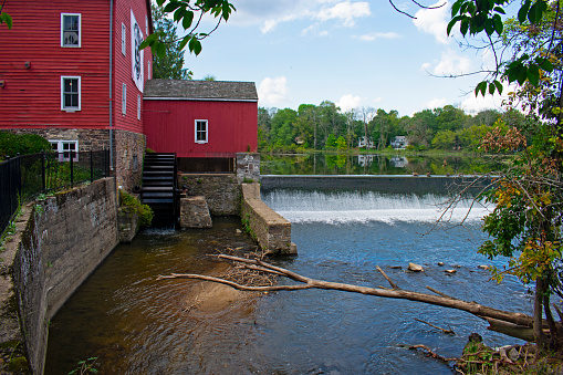 Scenic view of the historic Red Mill in Clinton, New Jersey, on a sunny day, with a waterfall in the foreground