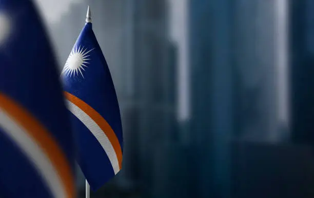 Small flags of Marshall Islands on a blurry background of the city.