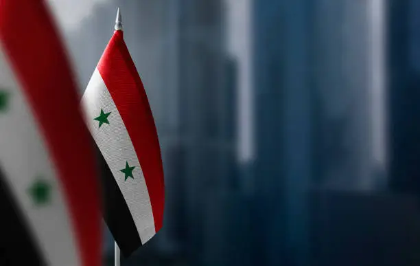 Small flags of Syria on a blurry background of the city.