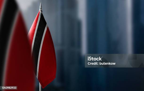 Small Flags Of Trinidad And Tobago On A Blurry Background Of The City Stock Photo - Download Image Now