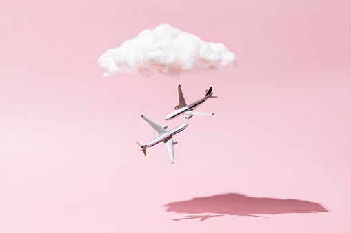 Concept of a white airplanes flying over white clouds on pink background. Copy space
