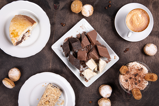 Sweet desserts on wood background. Traditional Italian sweet food - Cakes, chocolate, biscuits, coffee, tiramisu. Top view, flat lay