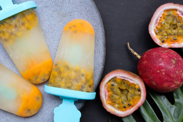 istock Homemade passion fruit juice popsicles with passion fruit half slice on black background.  Frozen fruit juice, Healthy summer food concept. 1343987796