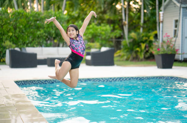 istock Hispanic girl jumping in swimming pool 1343990536