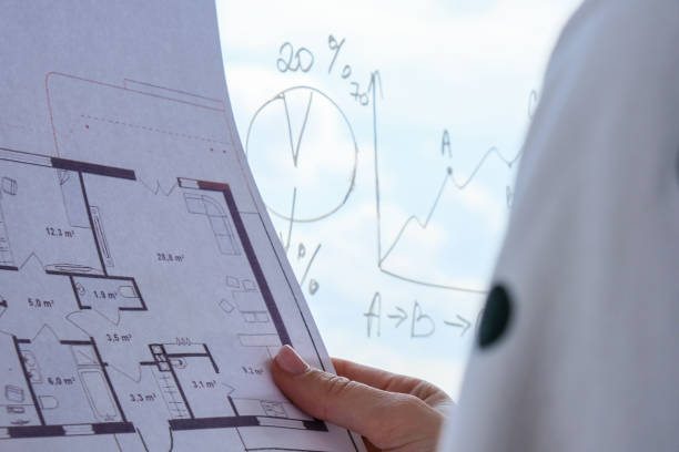 istock Female interior designer drawing house plan in office. Workplace Workspace window. Architect at work. Architectural construction plans with blueprints 1343992502