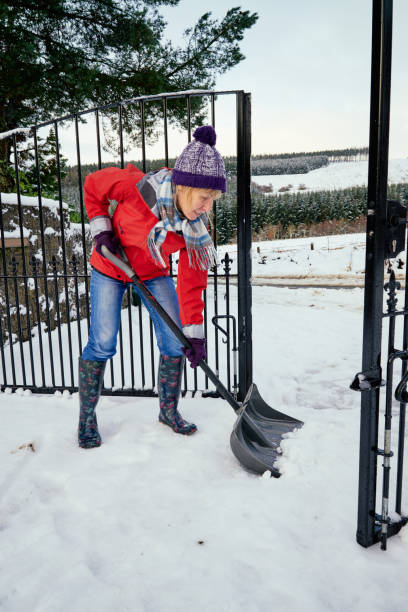 istock Senior woman clearing snow from her front yard using a snow shov 1344000306