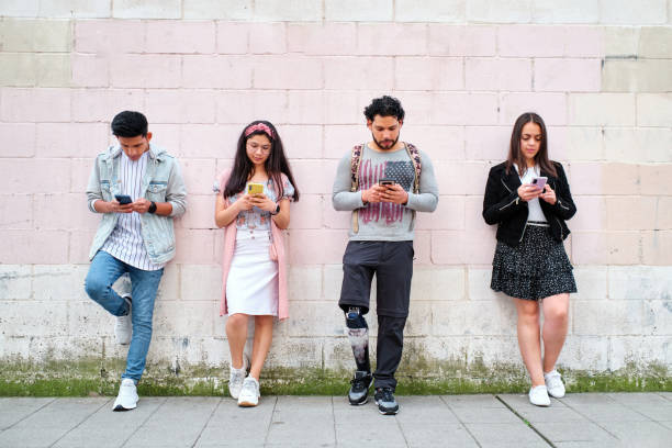 istock Four people standing leaning on street wall using their phones 1344000374