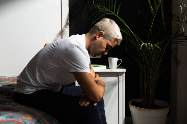 Depressed hispanic man Depressed hispanic man sitting on his bed thinking on his problems. Stress, anxiety, depression and mental health concept. sad gay stock pictures, royalty-free photos & images