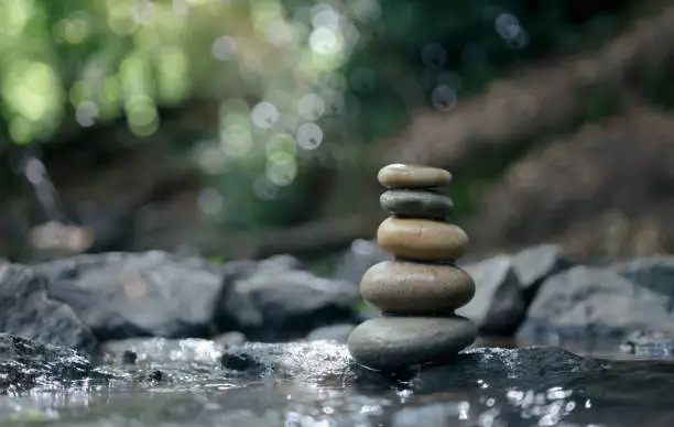 Photo of Stack of zen stones, Close up of pebble rocks stacked on top of each other in stream leading to a waterfall in a forest, Zen like concepts