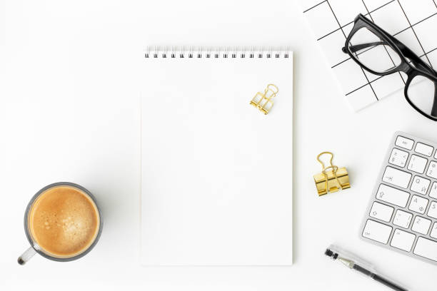 istock Blank notepad, cup of coffee, keyboard, eyeglasses, pen, notebook, binder paper clip on white background. Modern blogger workspace mockup. Online business or education concept. Copy space, flat lay 1344002724