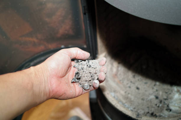 a dirty hand removing ash from wood burning fireplace or stove, indoor closeup