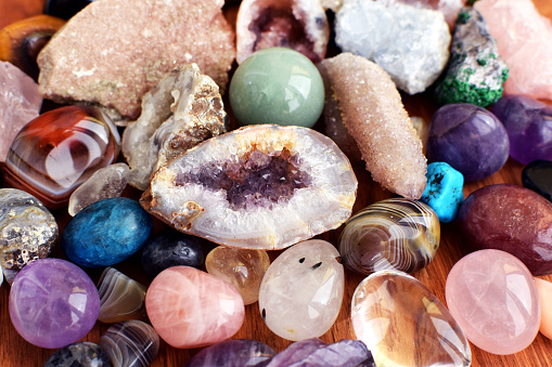 Beautiful gemstones,  geode amethyst and druses of natural purple mineral amethyst on a wooden background. Amethysts and rose quartz. Large crystals of semi-precious stones. 