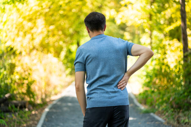 istock Back pain when walking outdoors, man with kidney inflammation on nature background 1344007482