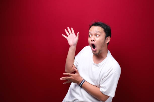 istock Young asian man is surprised and shouting wow with pointing right with his hand isolated on red background. 1344008506