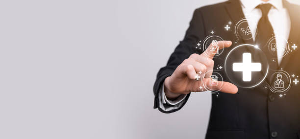 istock Businessman hold virtual plus medical network connection icons. Covid-19 pandemic develop people awareness and spread attention on their healthcare.Doctor,document,medicine,ambulance,patient icon. 1344015194