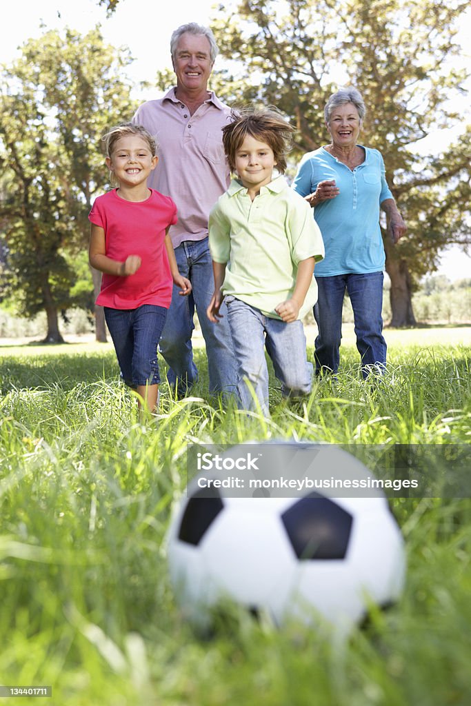 Abuelos jugando al fútbol con sus nietos - Foto de stock de Abuelos libre de derechos