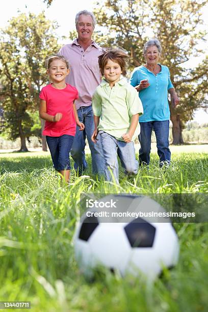 Abuelos Jugando Al Fútbol Con Sus Nietos Foto de stock y más banco de imágenes de Abuelos - Abuelos, Aire libre, Correr