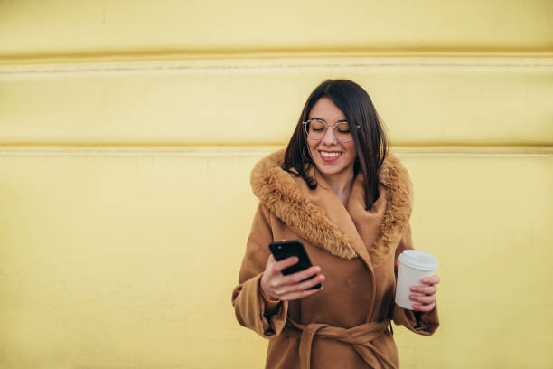 istock Young hispanic woman using a smartphone and a coffee takeaway 1344019976