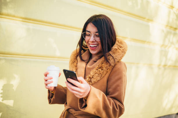 istock Young hispanic woman using a smartphone and a coffee takeaway 1344019989