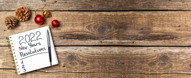 istock New year Resolutions 2022 on desk. 2022 Resolutions with notebook, Christmas ornaments on wooden background. Goals, plan, strategy, list, idea concept. New Year 2022 1344021739