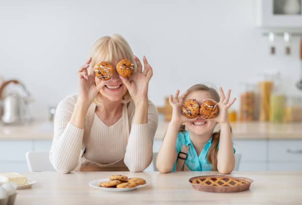 キッチンで食べ物で遊ぶおばあちゃんと孫娘 - grandmother pie cooking baking ストックフォトと画像