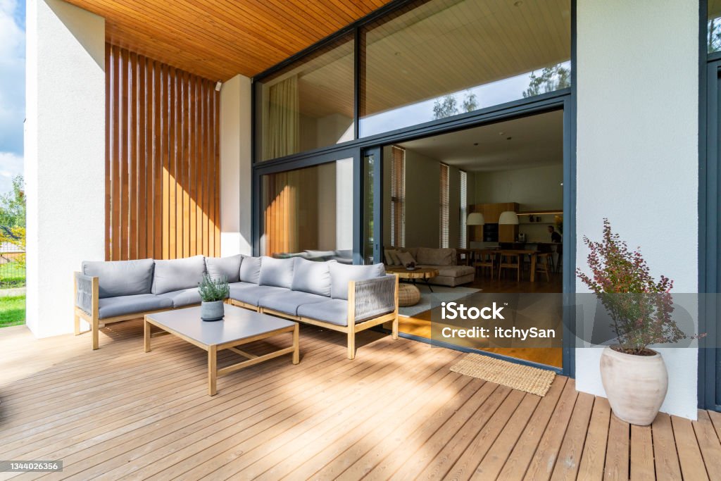 Cozy patio with entrance to the house Wooden patio connected to a private building, with seating area and cozy lounge zone, open window with entrance to the house. Patio Stock Photo