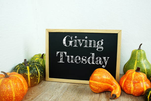 istock Giving Tuesday typography text on board easel mock up with Artificial flowers and pumpkin on wooden table interior decoration 1344027145